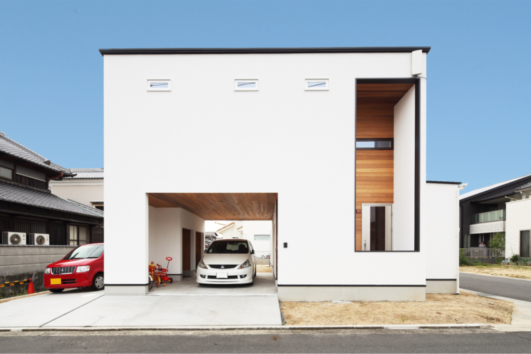 インナーガレージと縦長窓が特徴的な、白を基調としたモダンデザインの外観