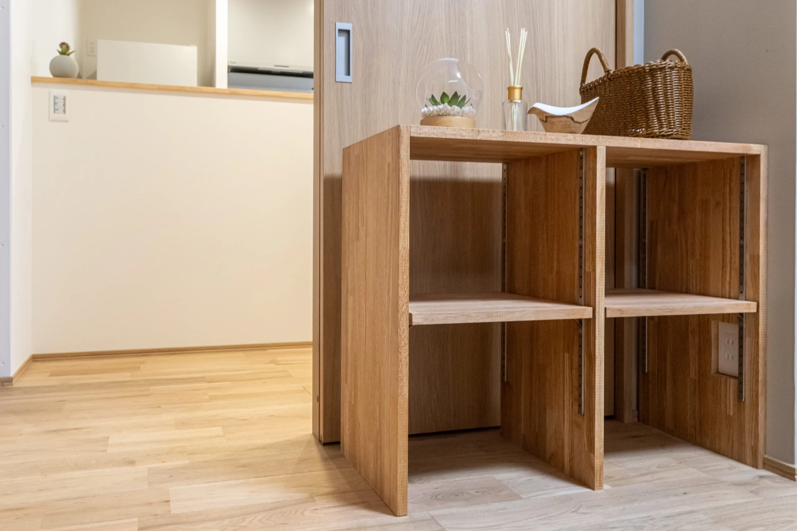 木目の床と引き戸の前の、雑貨が飾られたオープンタイプの造作棚