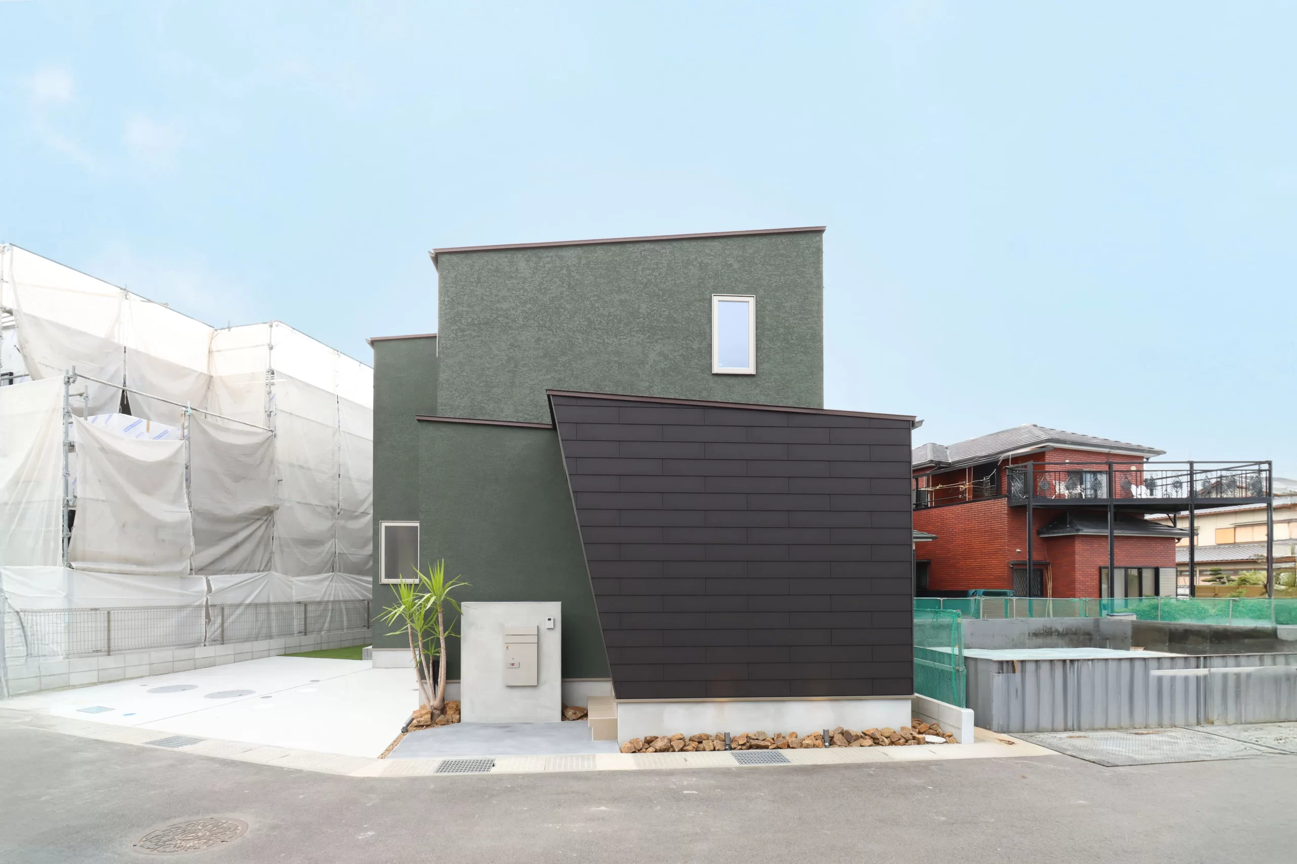 グリーンの塗り壁とLAP-WALLを組み合わせたシンプルでモダンな新築住宅の外観