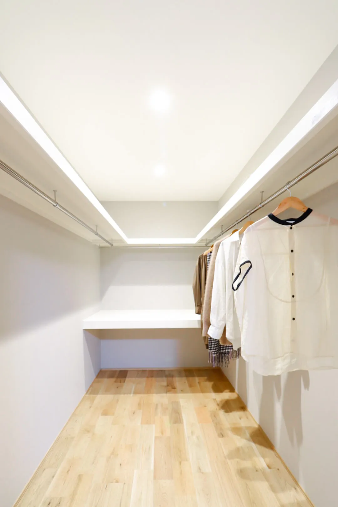 無垢フローリングの床と棚、ハンガーパイプがある広いウォークインクローゼット