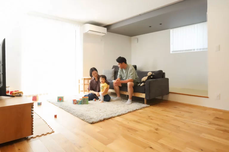無垢材の床と自然光が差し込む明るいリビングで遊ぶ家族の様子