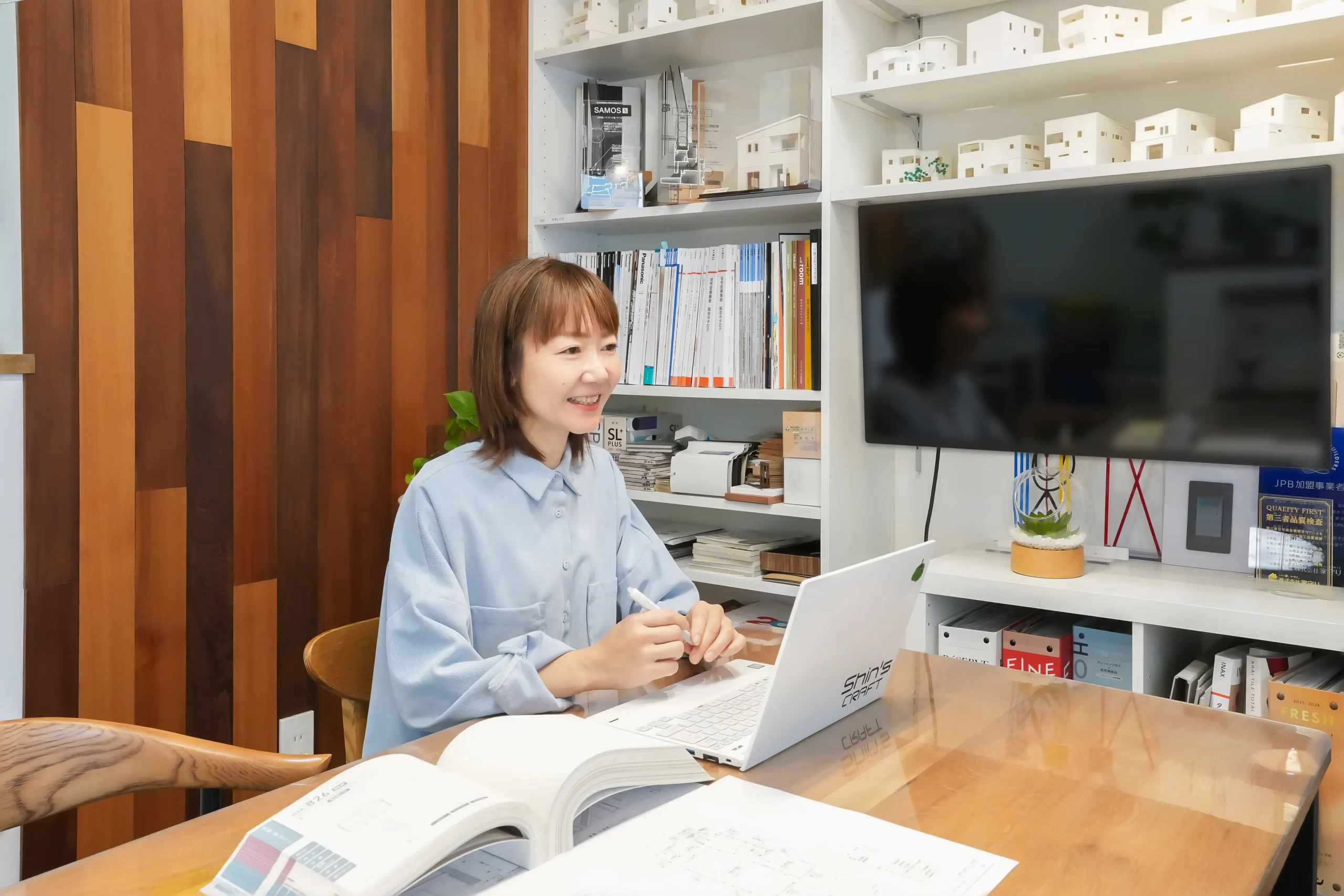 弊社の女性建築士、小野寺登志美が事務所で笑顔でお客様と接客する様子