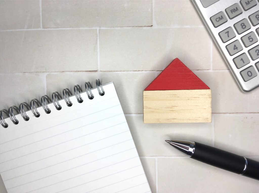 家の積み木とノート、ペン、電卓が映っている写真