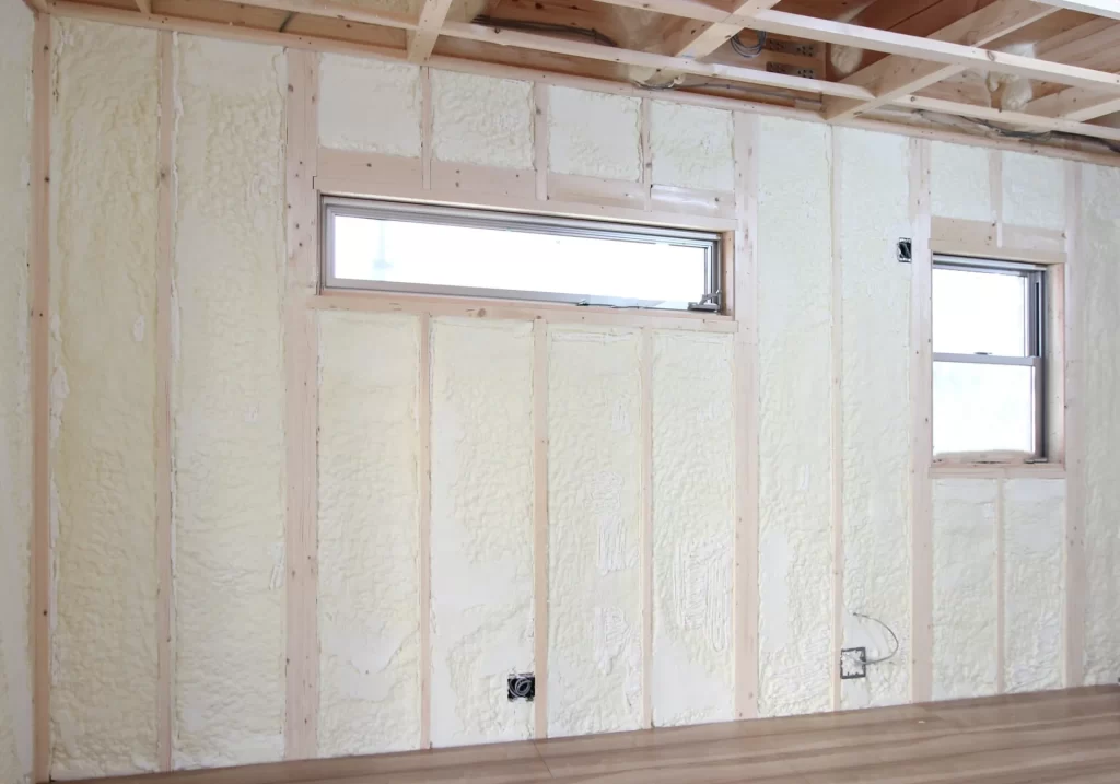 住宅の壁面に隙間なく吹き付けられた発泡ウレタン断熱材の施工現場写真で、高い断熱性能と気密性を確保するための家づくりにおける重要な工程を写したもの。