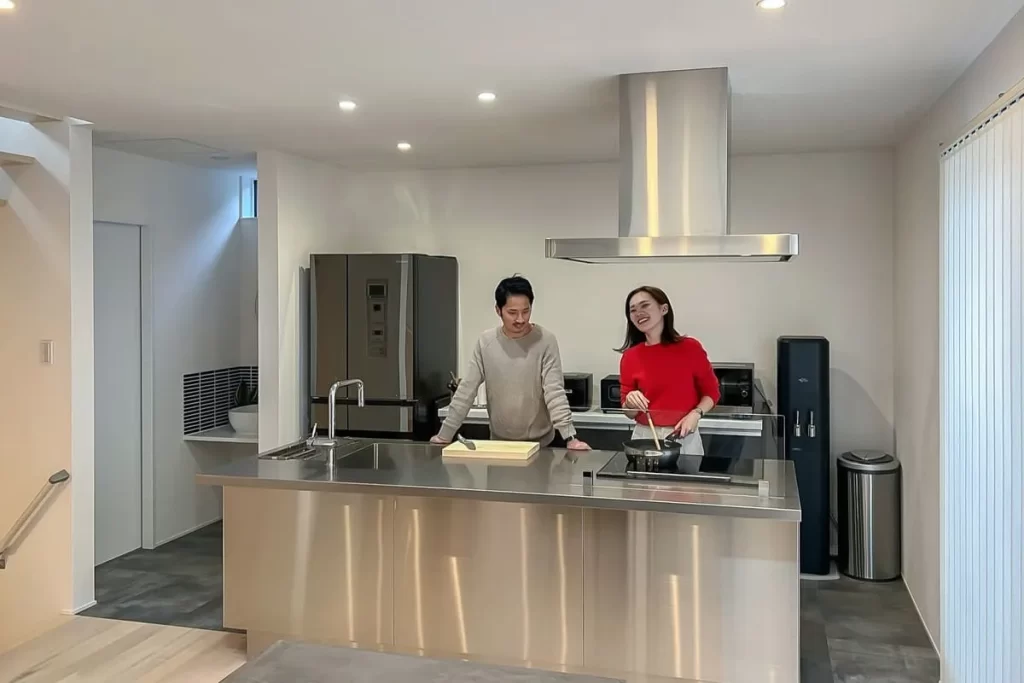 開放的なアイランドキッチンで夫婦が楽しそうに会話をしながら料理をしている、株式会社シンズクラフトが提案する「家族の会話が弾むLDK」の施工事例。