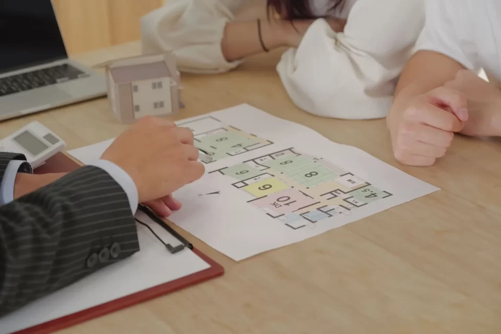 間取り模型や資料を見ながら、家族にとって暮らしやすいLDKの広さや動線について相談している家づくり打ち合わせ風景。