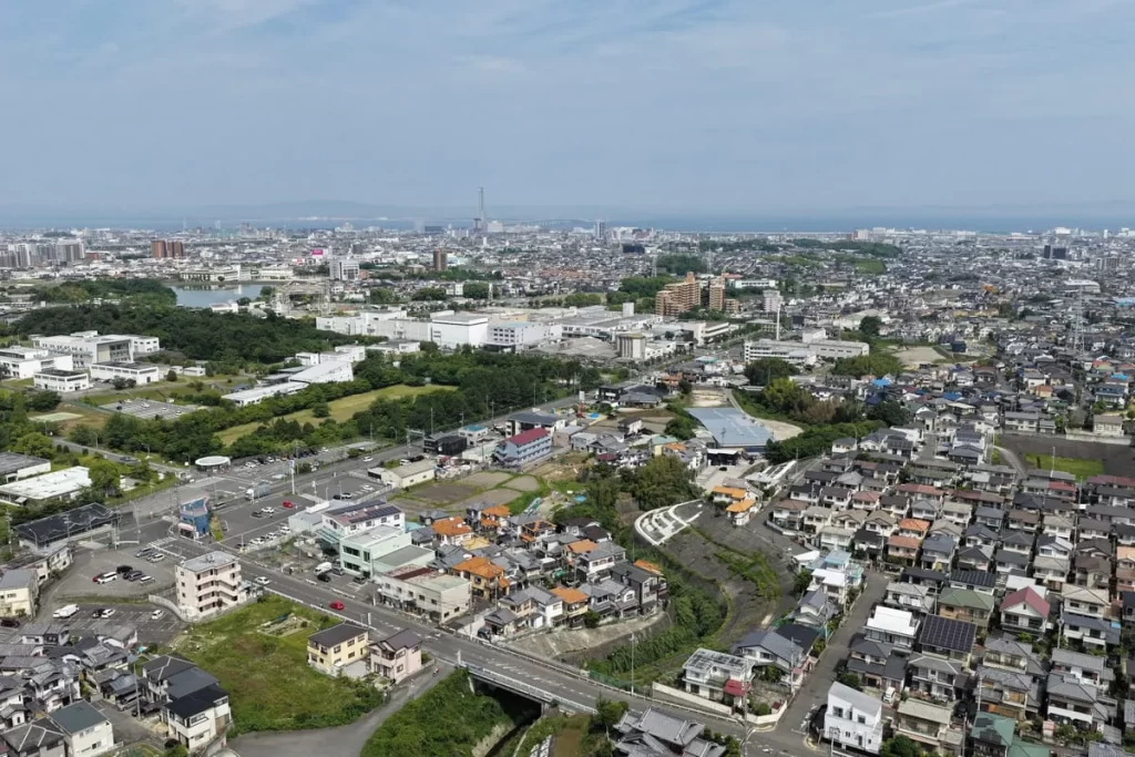 青空の下に広がる住宅街を高い視点から撮影した風景写真で、注文住宅の土地探しや地域環境の検討をイメージした広大な街並みのカット。