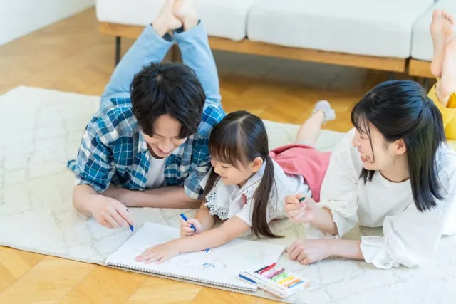 明るいリビングで笑顔を見せ合う両親と子ども。家族がゆったりと過ごせる理想的なリビング・ダイニング・キッチン。