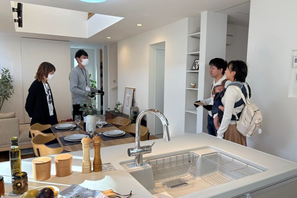 完成見学会で、実際のキッチンや吹き抜けの開放感を体感するご家族とスタッフ。