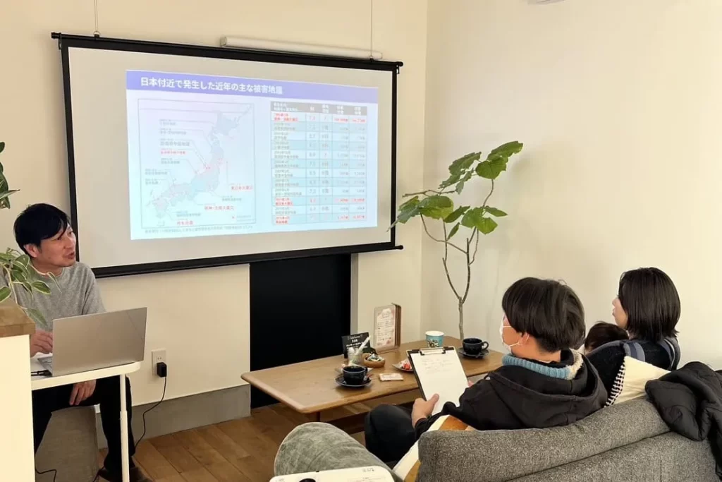 プロジェクターで地震被害のデータを投影し、熱心に説明を聞く家族向けの家づくり勉強会の風景。