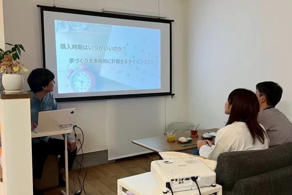 プロジェクターに映し出されたカレンダーを見ながら、資金計画セミナーに参加する家族の様子。