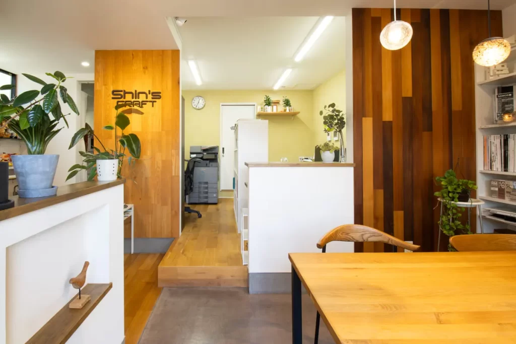 シンズクラフトのロゴが掲げられた、木のぬくもりを感じるナチュラルで清潔感のあるオフィス内観。