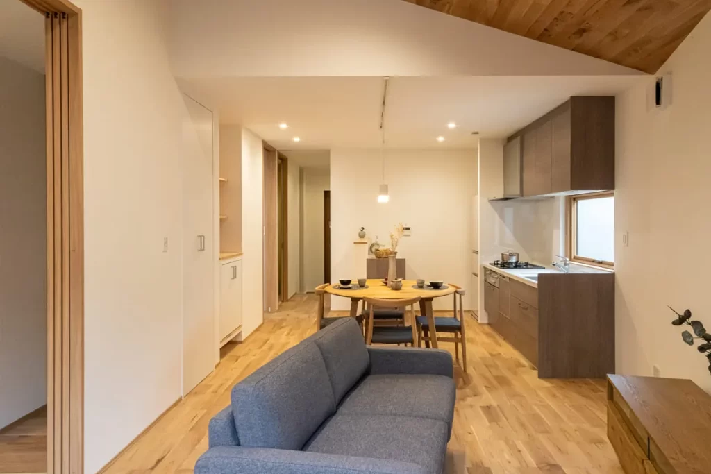 木の温かみがある勾配天井のリビングと、整理されたキッチン・ダイニングの室内風景。