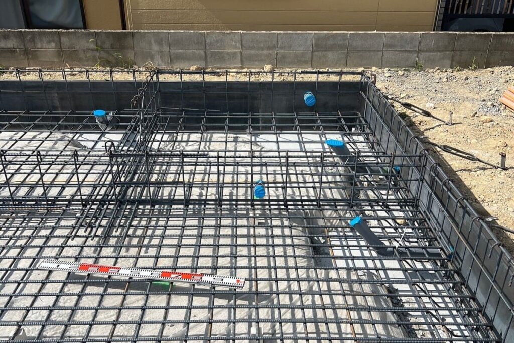 住宅の基礎工事における配筋検査の様子。コンクリートを打設する前の鉄筋が精緻に組み上げられている現場写真。